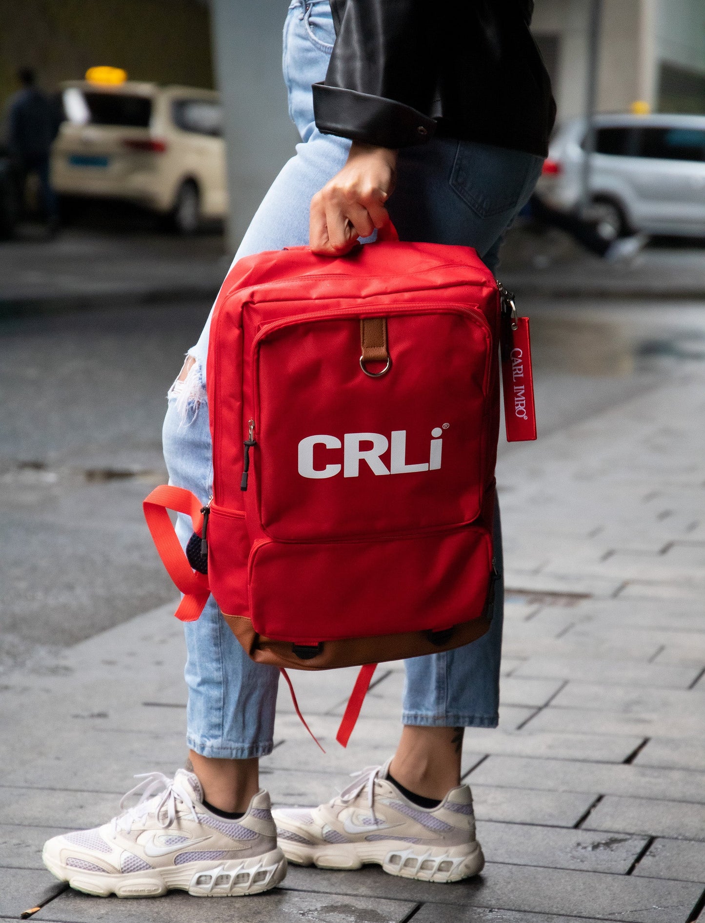 Sac à dos rouge CRLi, vue arrière, fermeture zippée et poche avant avec sangle.