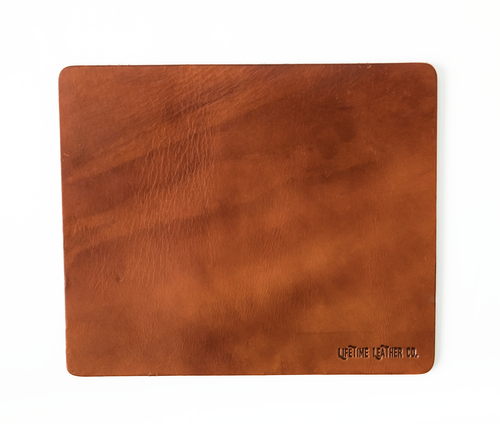 Tapis de souris en cuir marron clair, surface texturée et logo en bas à droite