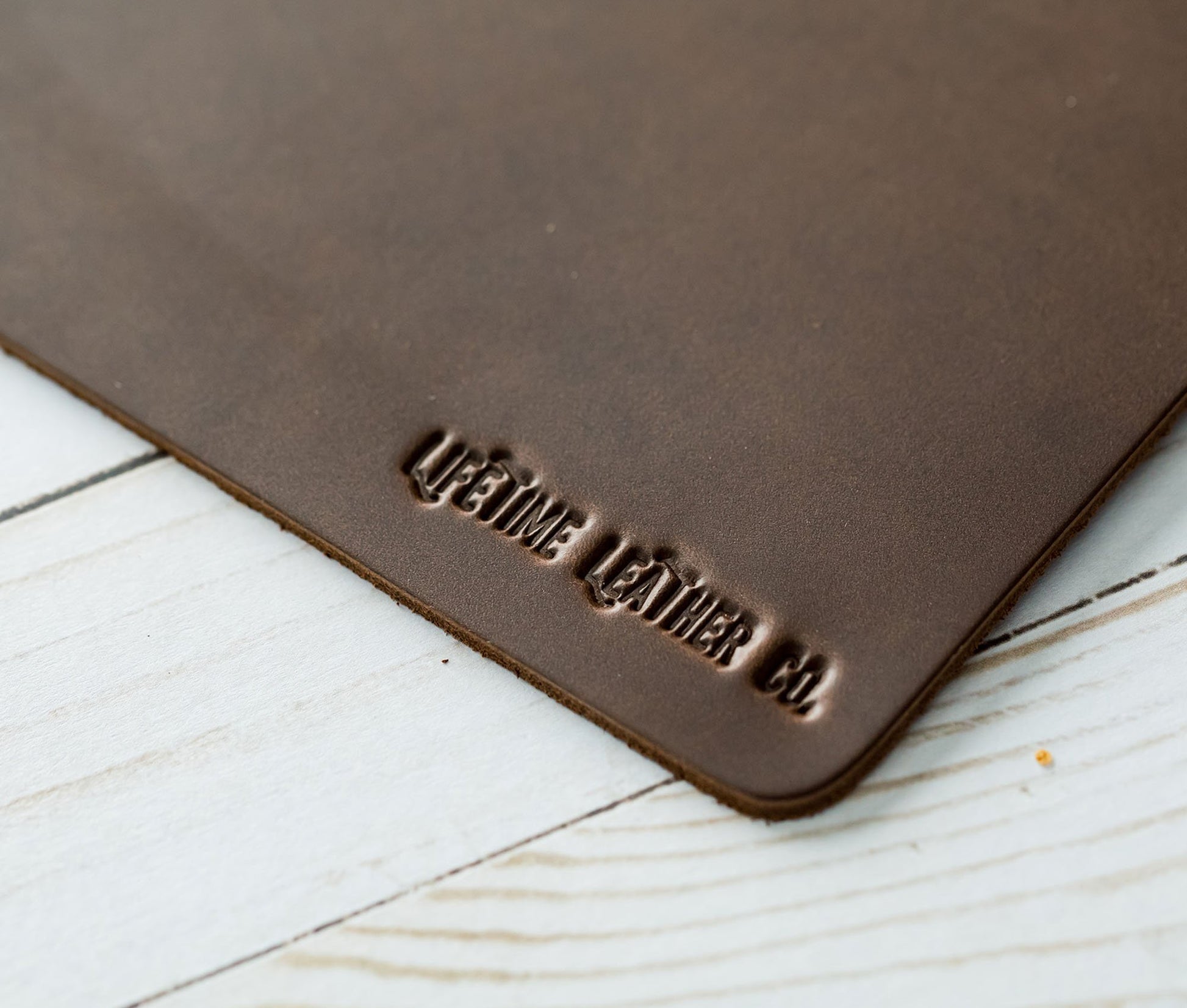 Tapis de souris en cuir marron foncé, angle et inscription « LIFETIME LEATHER CO. »