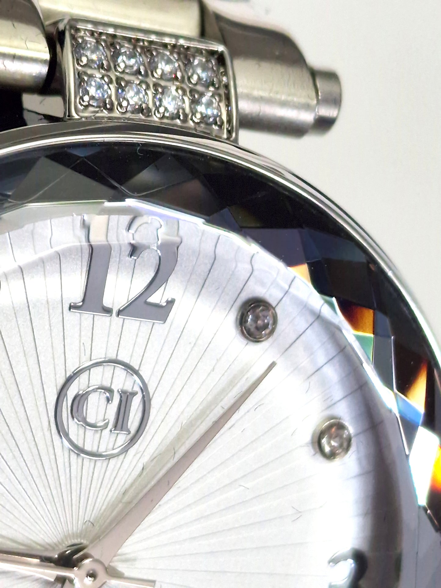 Gros plan montre homme: couronne sertie de pierres, cadran argenté, chiffre 12.