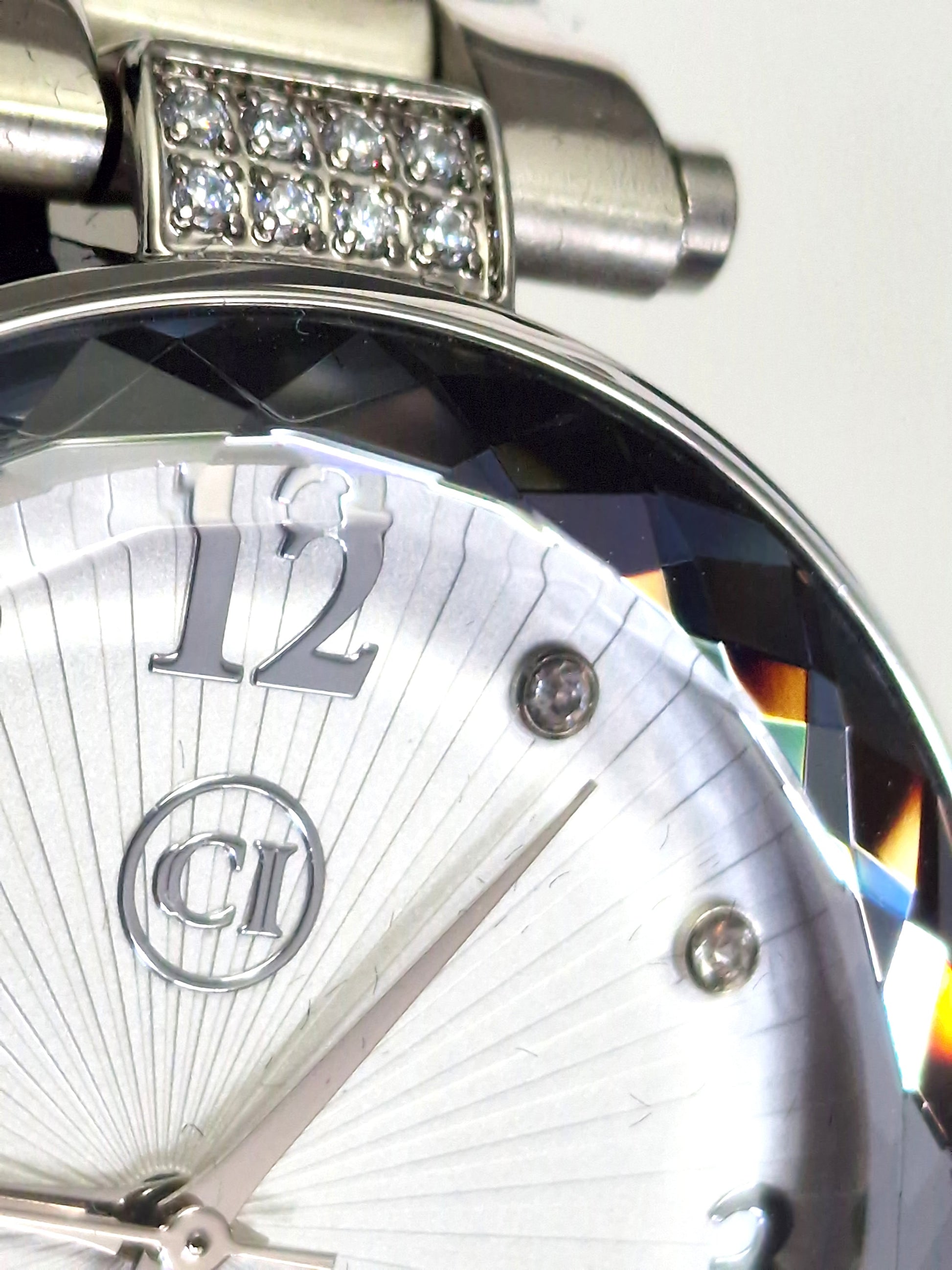 Gros plan montre homme: couronne sertie de pierres, cadran argenté, chiffre 12.