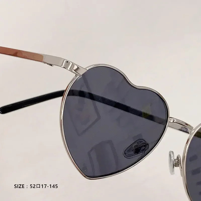Lunettes de soleil cœur, monture argentée et verres teintés foncés, gros plan