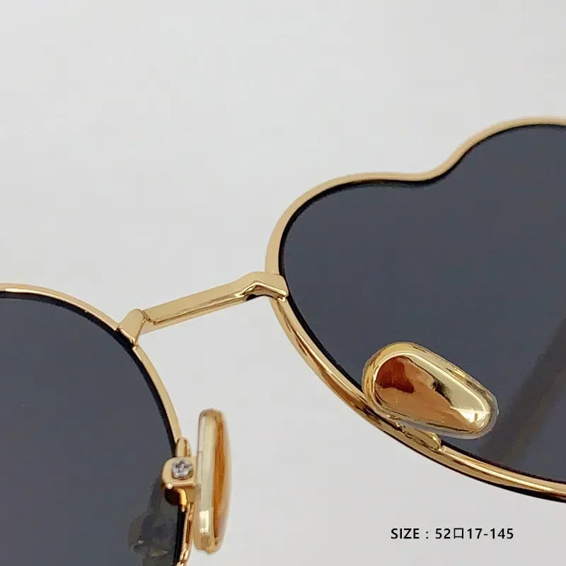 Lunettes de soleil cœur, monture dorée, détail de la charnière et des verres teintés