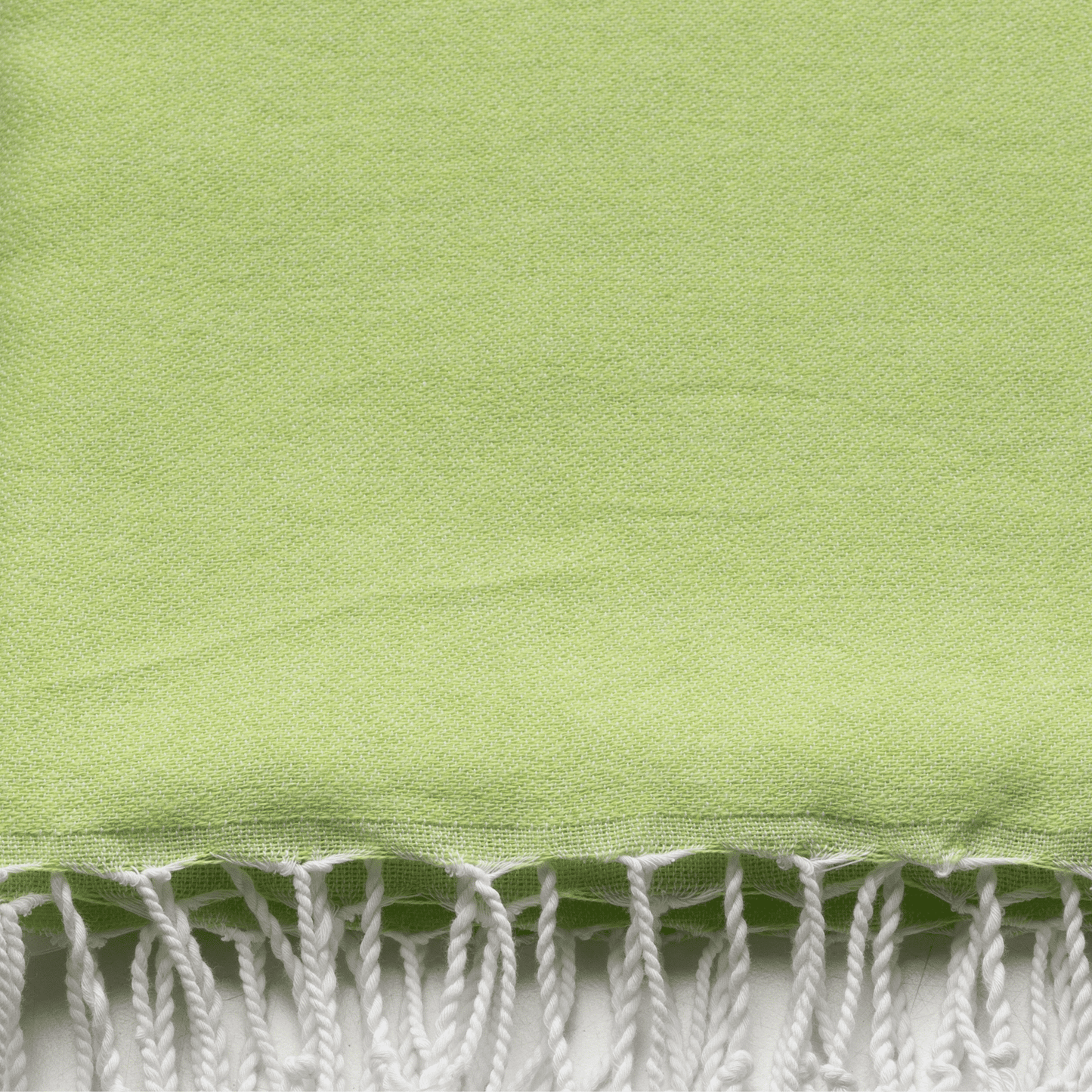 Bord frangé blanc sur tissu de serviette vert