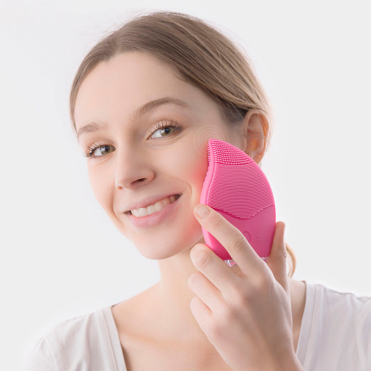 Nettoyeur-masseur facial en silicone rose, brosse en contact avec la joue