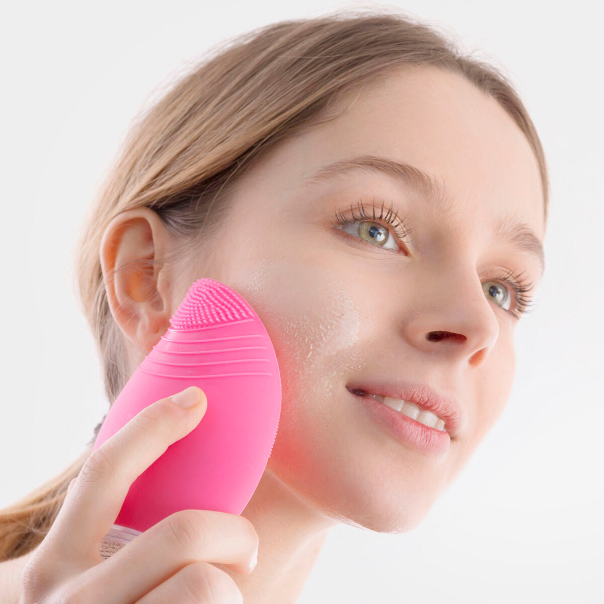 Nettoyeur-masseur facial rechargeable InnovaGoods rose, brosse silicone touchant la joue