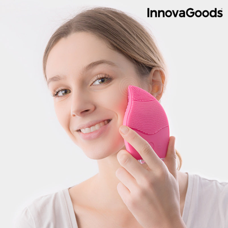 Nettoyeur-masseur facial en silicone rose, appliqué sur la joue