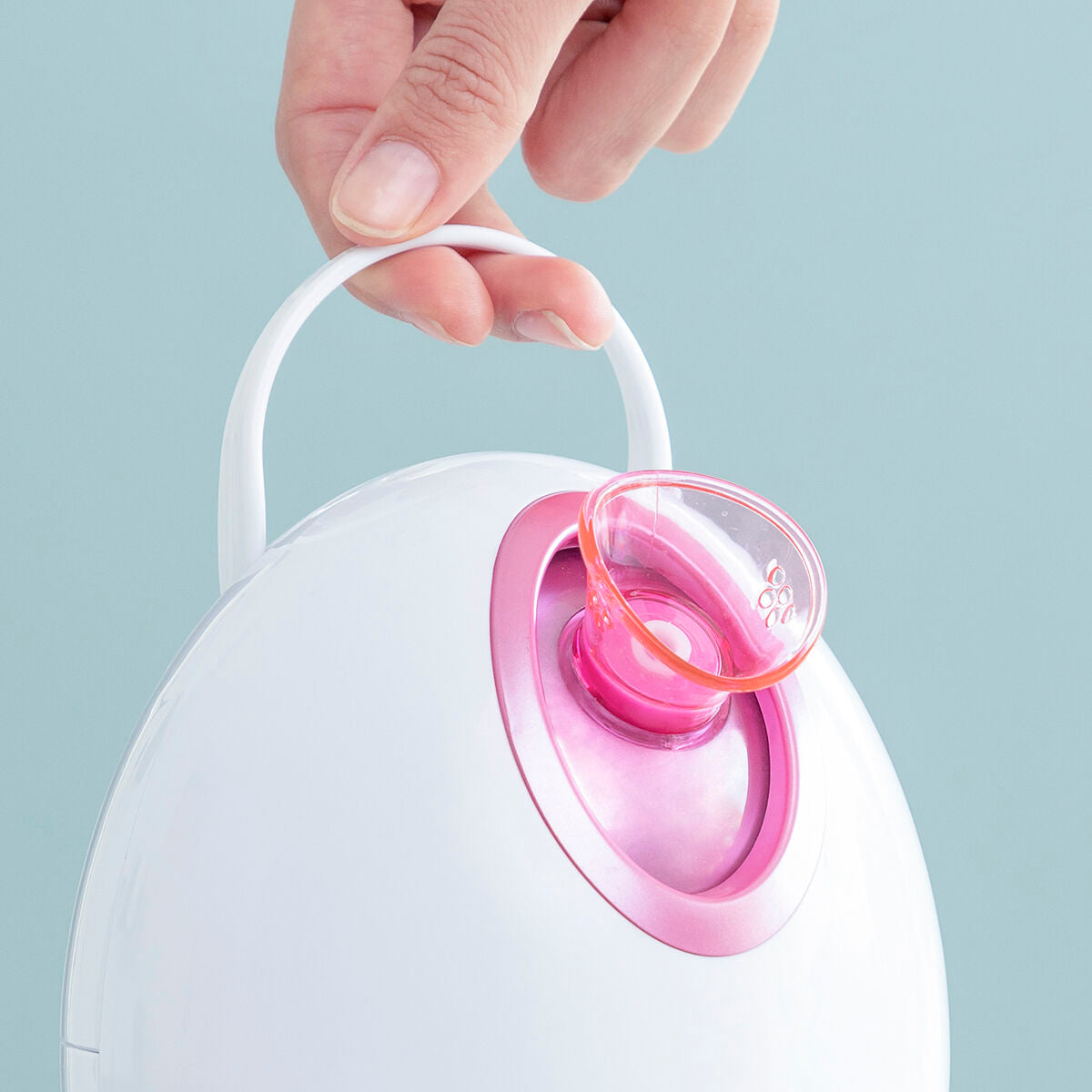 Sauna facial électrique, vue de la tête rose transparente sur l’appareil blanc