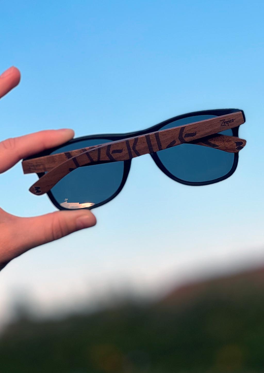 Lunettes Eyewood en noyer gravé, verres foncés polarisés, portées en extérieur