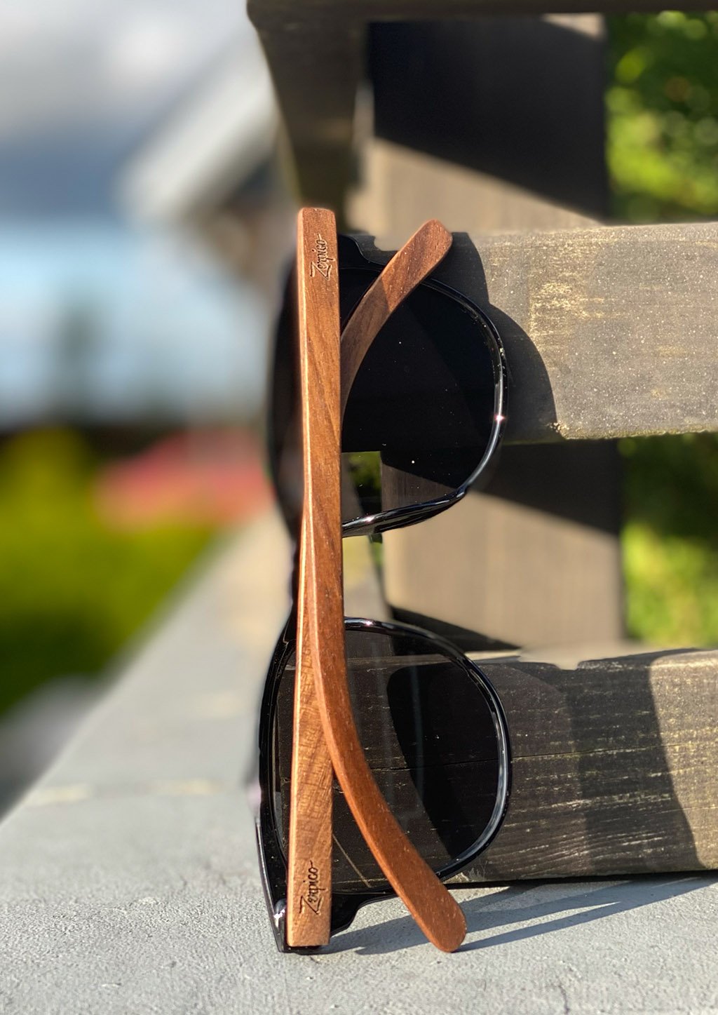 Lunettes de soleil avec verres foncés, branches en bois sur un support