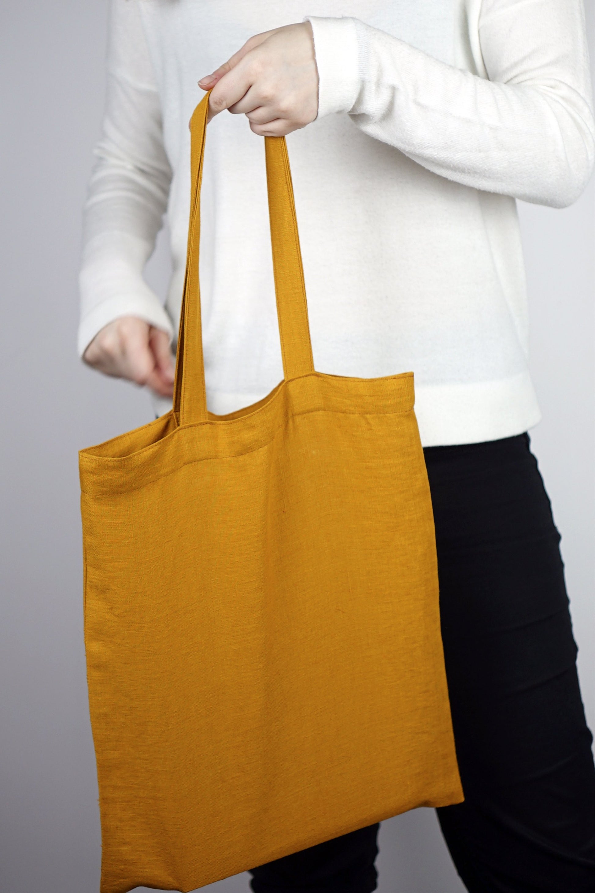 Sac fourre-tout en lin moutarde, grandes anses et ouverture supérieure.