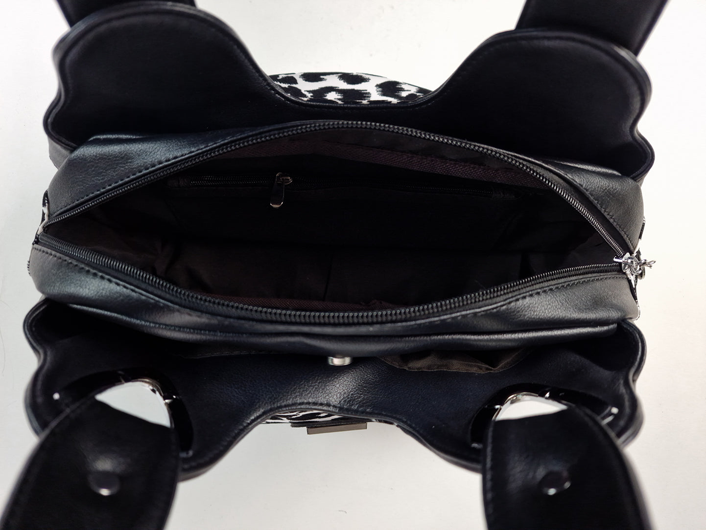 Sac à main imprimé léopard noir et blanc, intérieur noir et fermeture zippée visible.