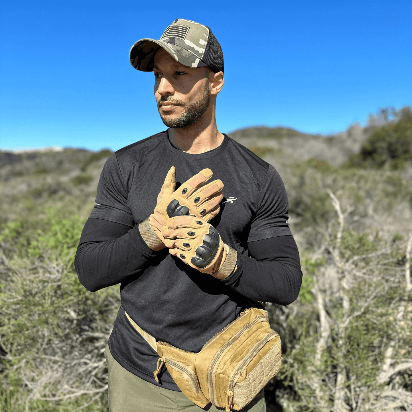 Gants tactiques beige et noirs portés par un homme, paume visible et protections aux jointures.