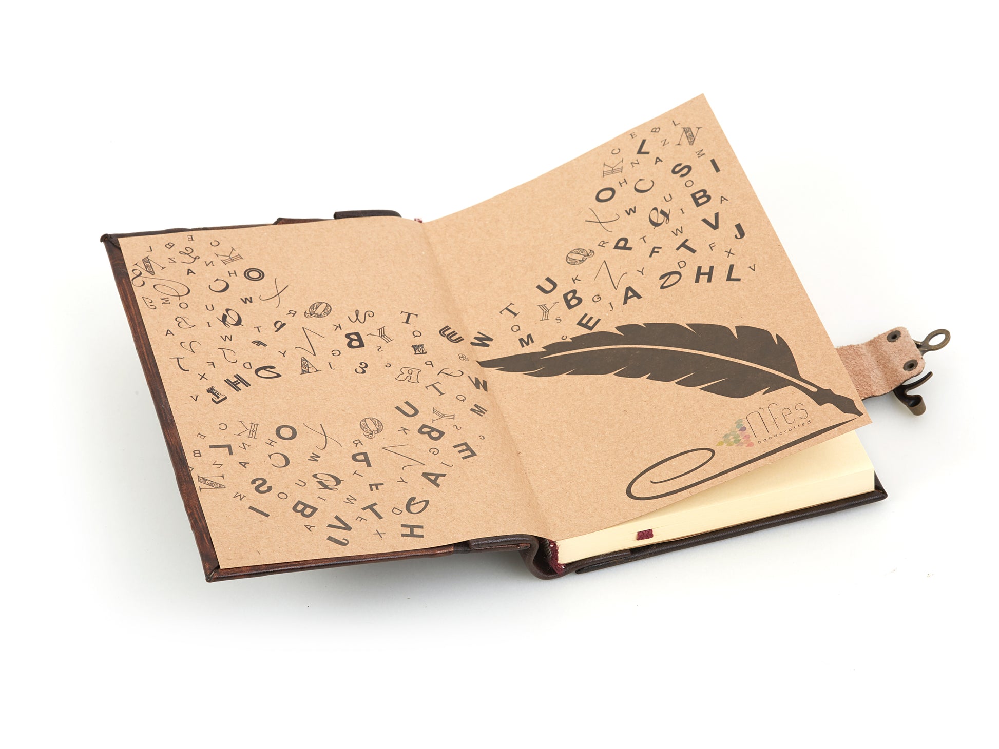 Carnet en cuir ouvert, pages crème imprimées d’un alphabet et d’une plume stylisée.