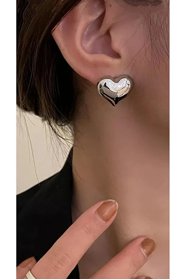 Boucles d’oreilles cœur argentées, clous brillants, portées sur l’oreille