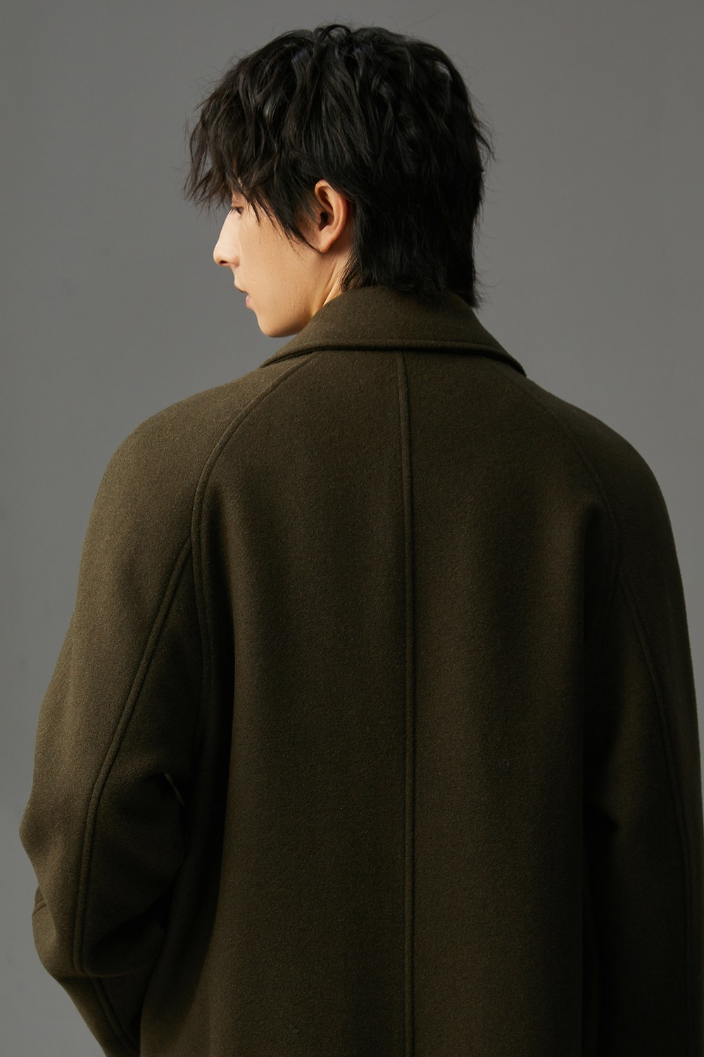 Manteau long en laine kaki, vue de dos, coutures centrales et col montant.