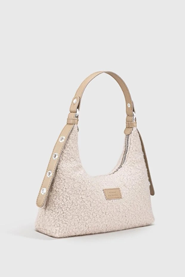Sac baguette en peluche tressée beige clair, anses en cuir et boucles métalliques.