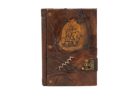 Carnet en cuir brun avec motif voilier gravé doré et fermeture à lanière.