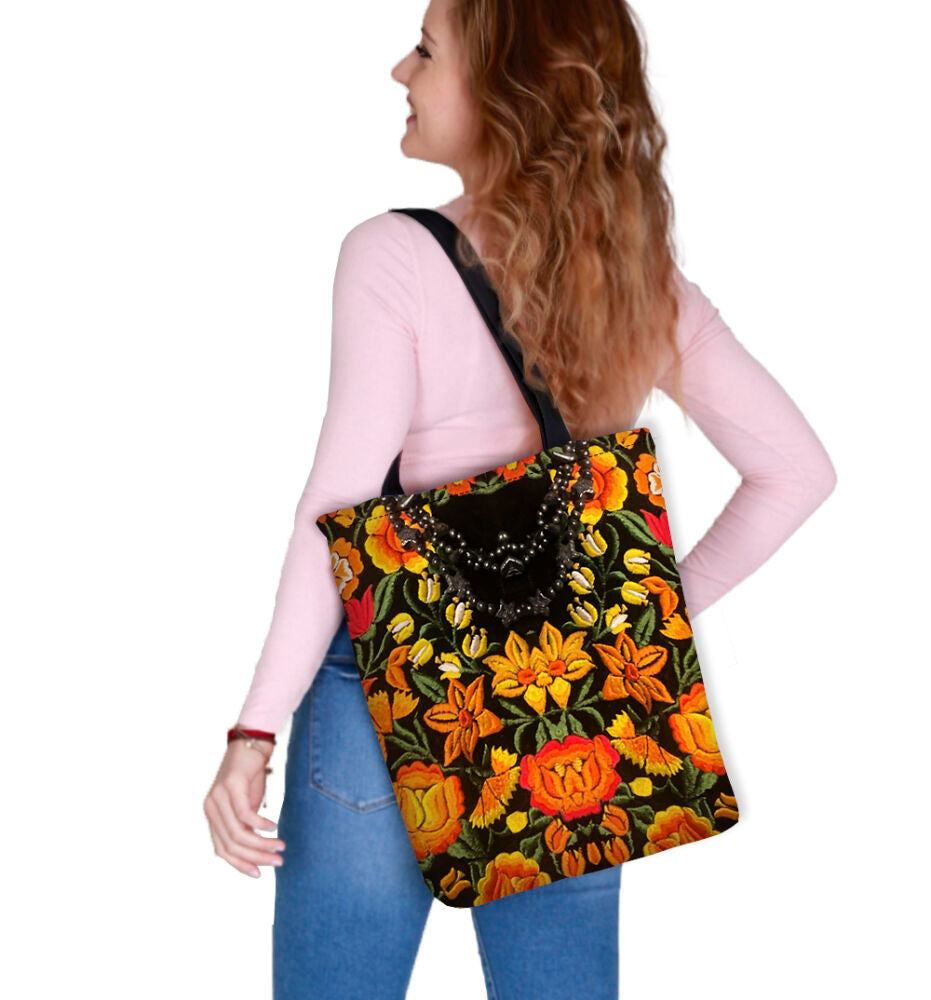 Sac bandoulière floral à anses noires porté sur l’épaule, motif orange et jaune