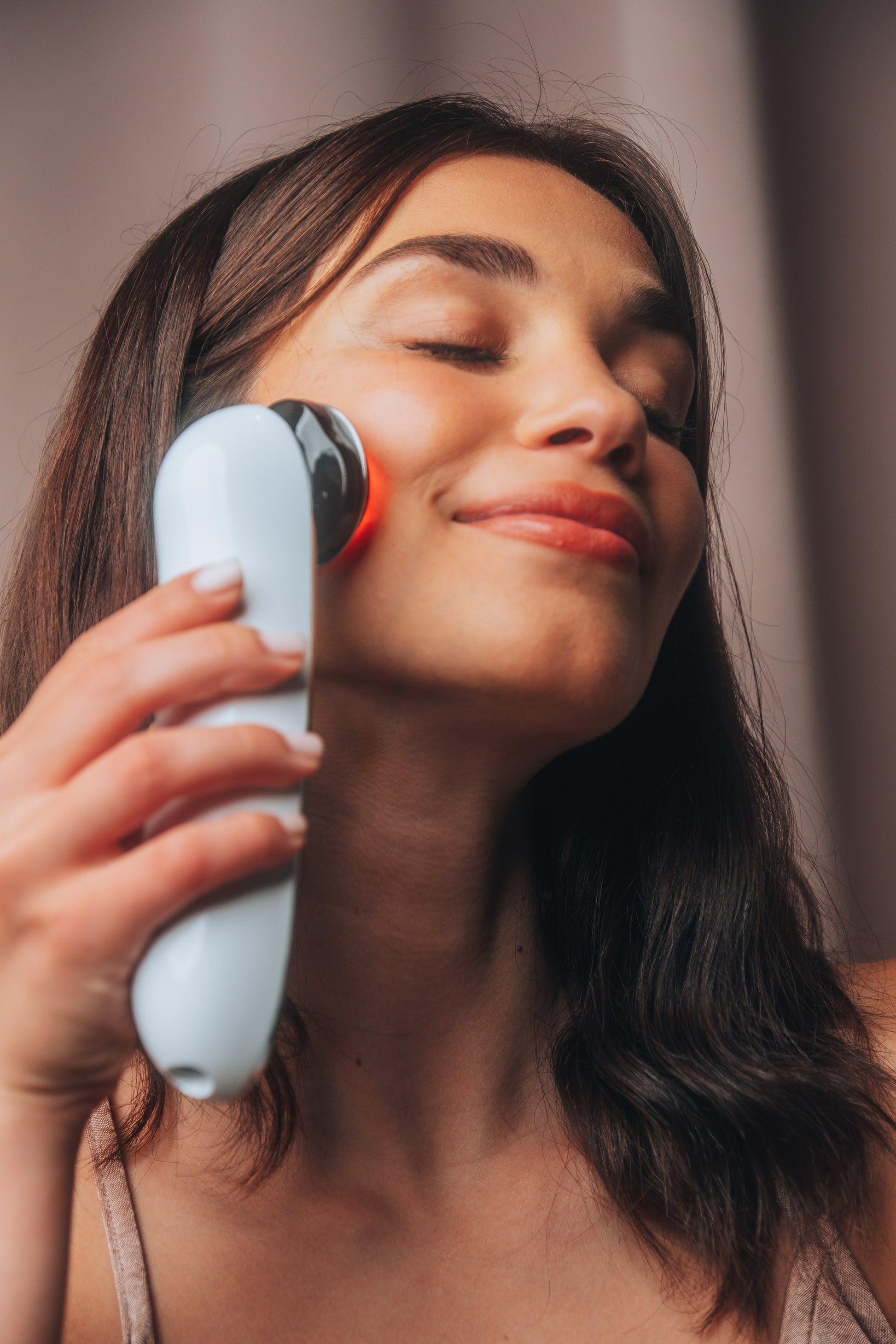Wand de radiofréquence COCOON SKIN près du visage, tête LED rouge sur l’appareil