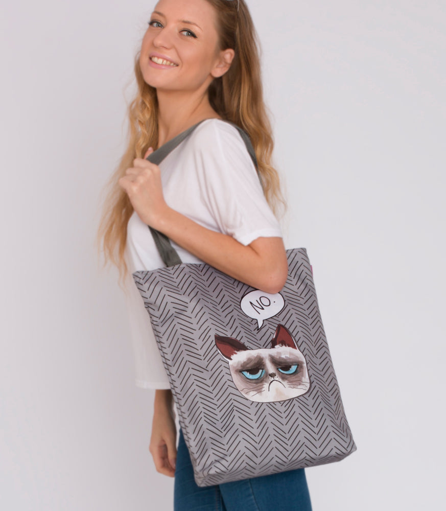 Sac cabas en toile grise à motif chevrons avec applique chat et anses noires.