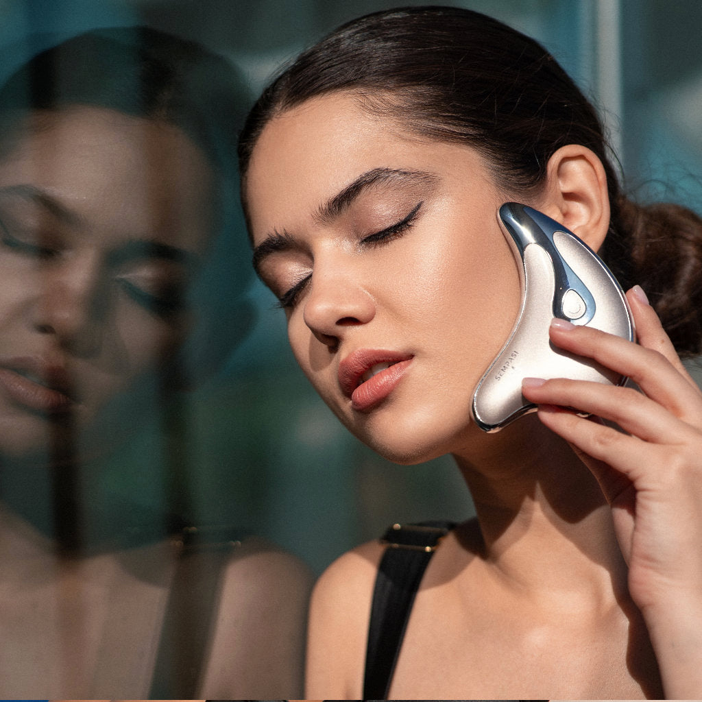 Appareil de yoga facial doré près du visage, forme goutte aux reflets bleus