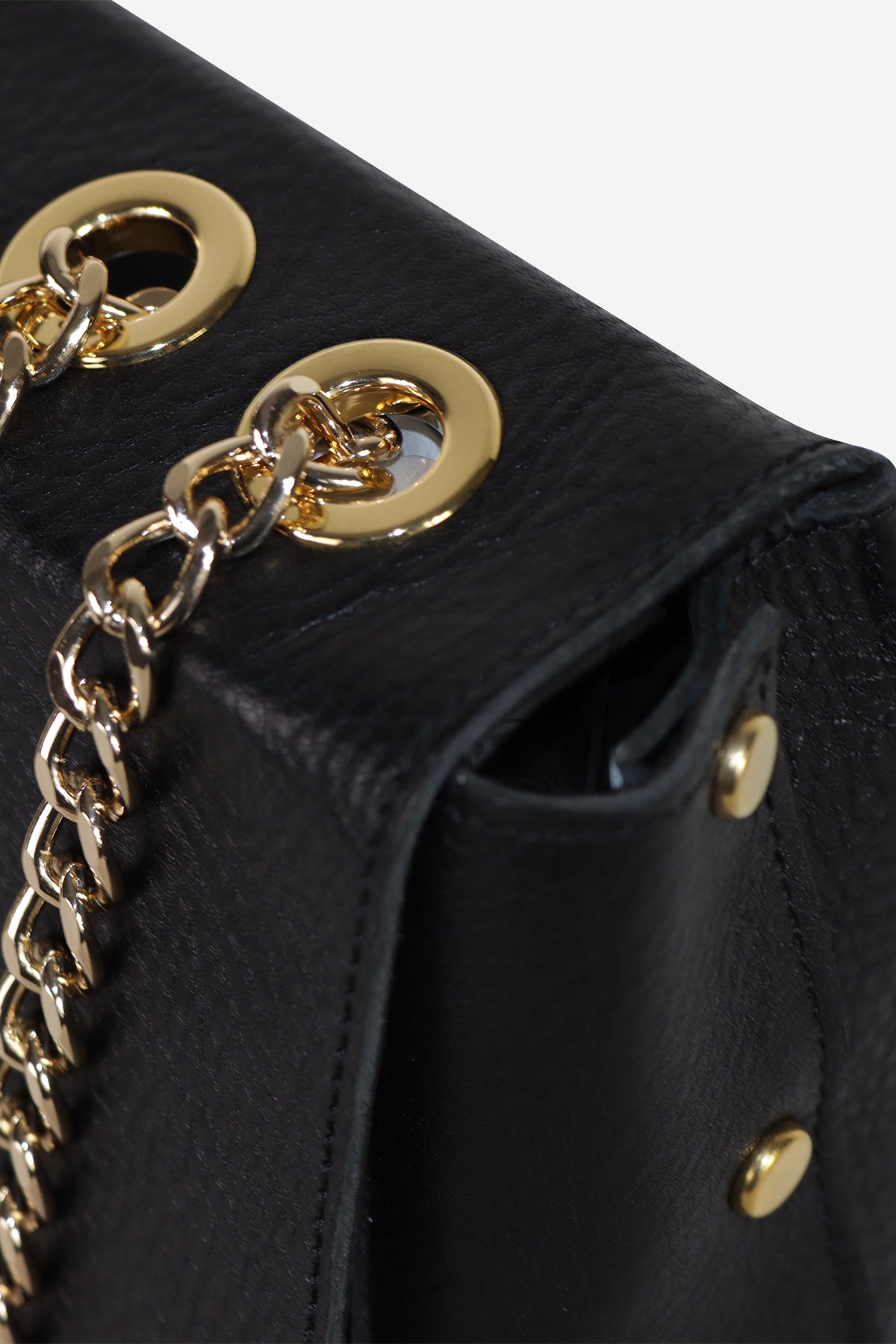 Partie du sac en cuir noir avec chaîne dorée et rivets sur le rabat.