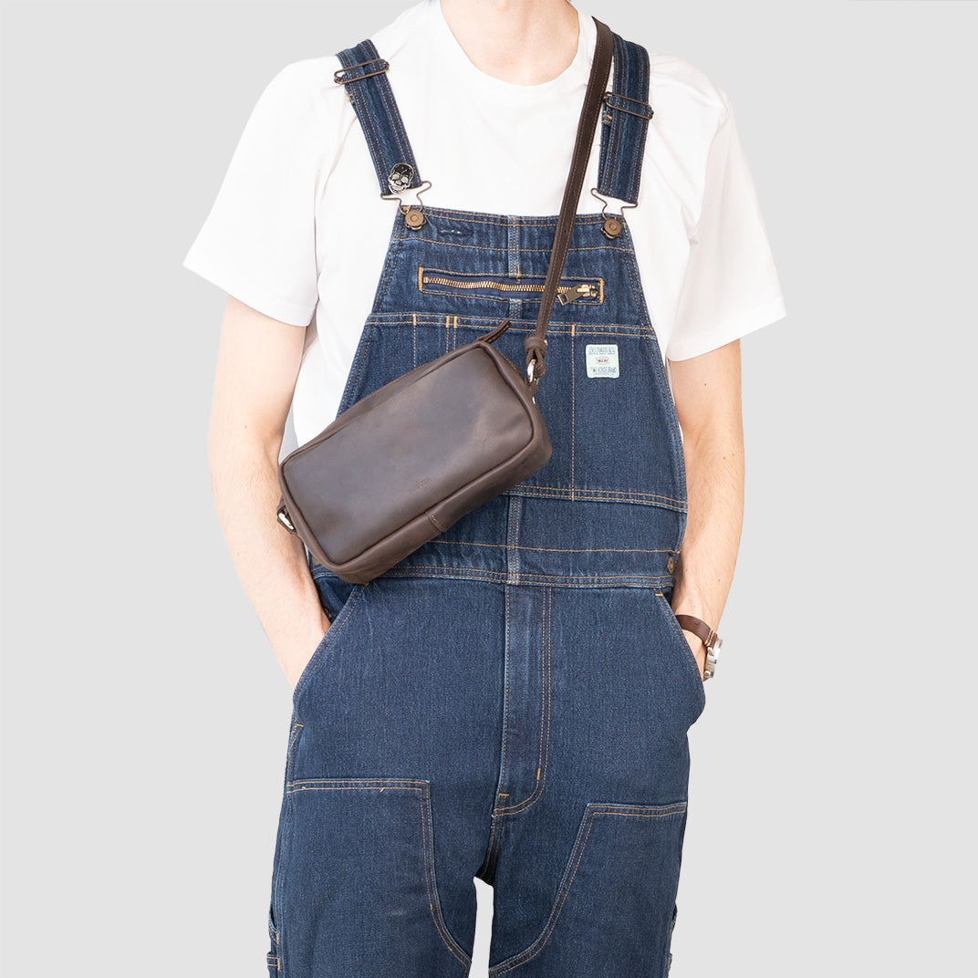 Mini sac besace en cuir noir porté en bandoulière par un modèle