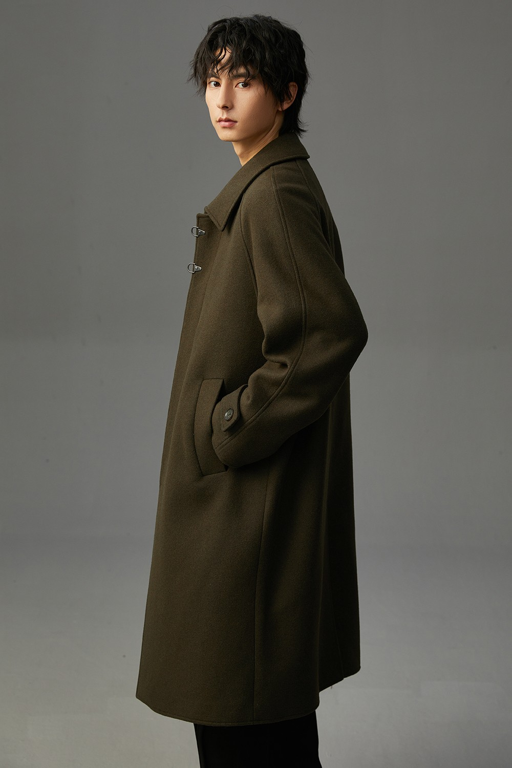 Manteau long en laine kaki, vue de profil, boutons duffle et col à revers.