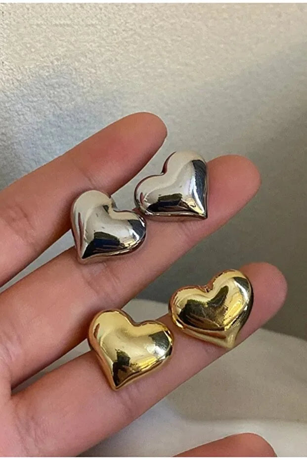 Boucles d’oreilles cœur, clous métal argenté et doré brillants sur main