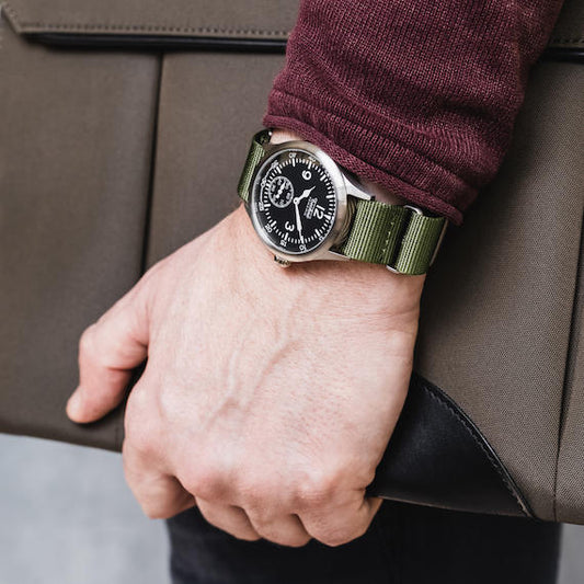 Montre-bracelet pour homme à cadran noir et bracelet nylon vert olive, avec boîtier acier.