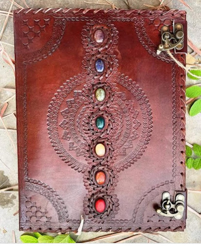 Carnet artisanal en cuir bordeaux, couture main et ornements floraux, fermoir métal.