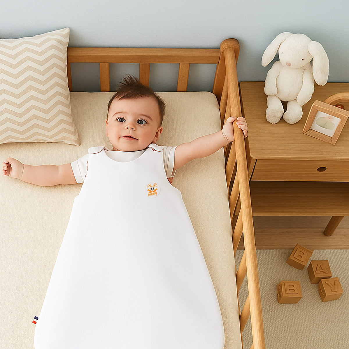 Gigoteuse bébé blanche avec intérieur à carreaux orange, col ouvert et motif brodé.