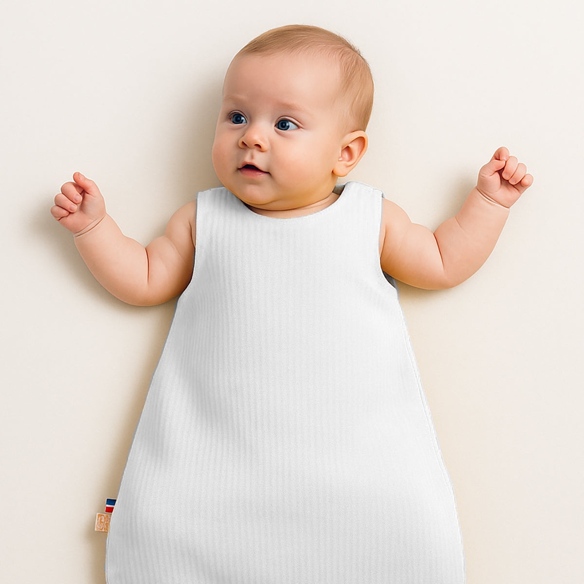 Gigoteuse blanche pour bébé, sans manches, portée par un bébé face