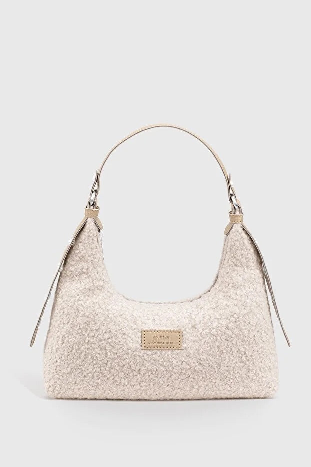 Sac baguette en peluche tressée beige clair, anses et petit logo rectangulaire.