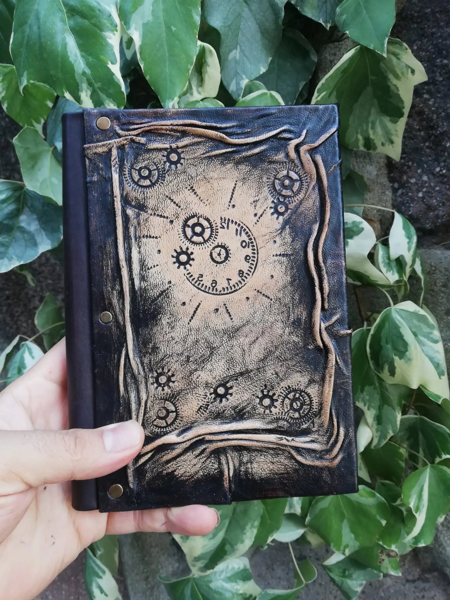 Carnet en cuir foncé avec motif engrenages et horloge, couture et œillets métalliques