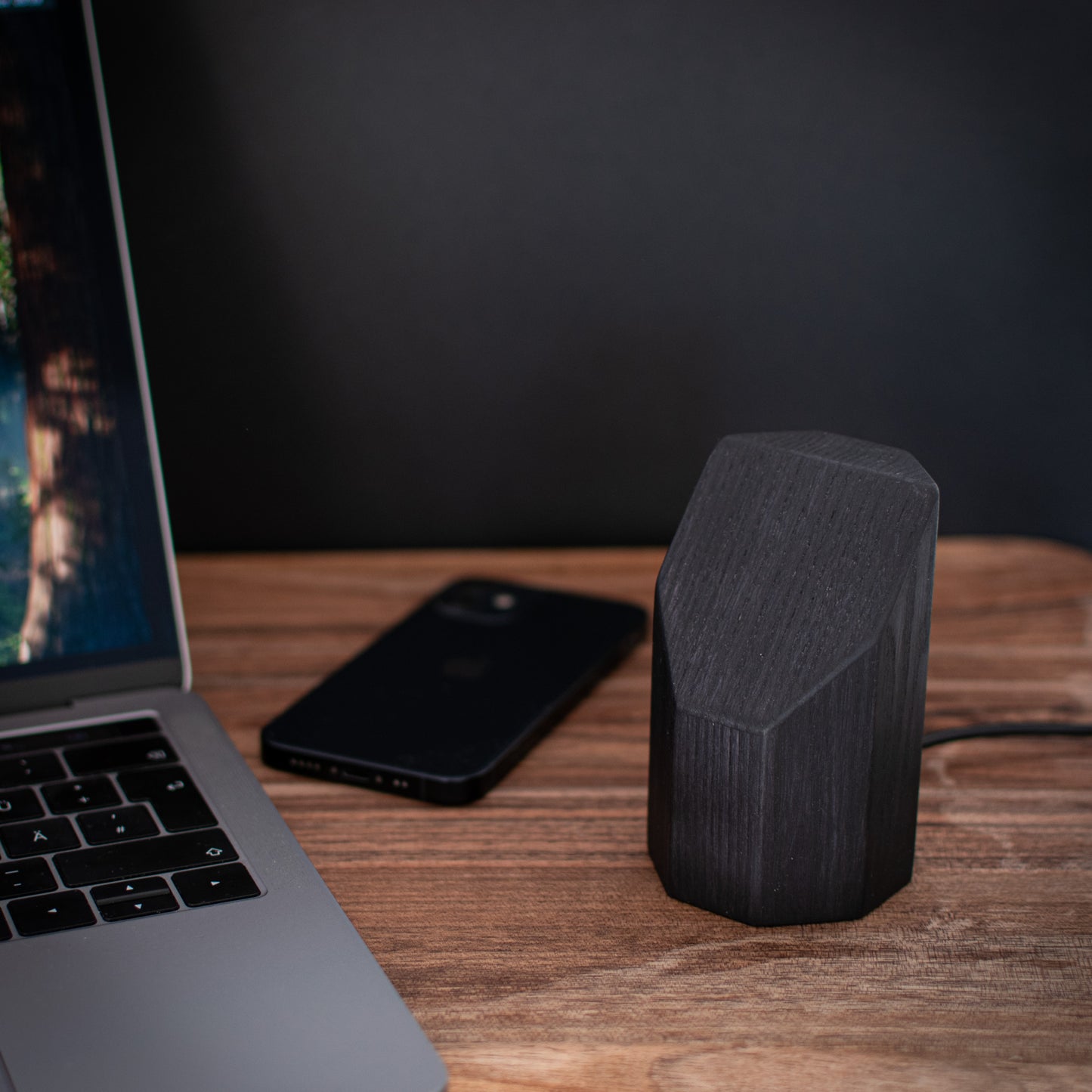 Chargeur sans fil sur socle en bois sombre, vu de côté
