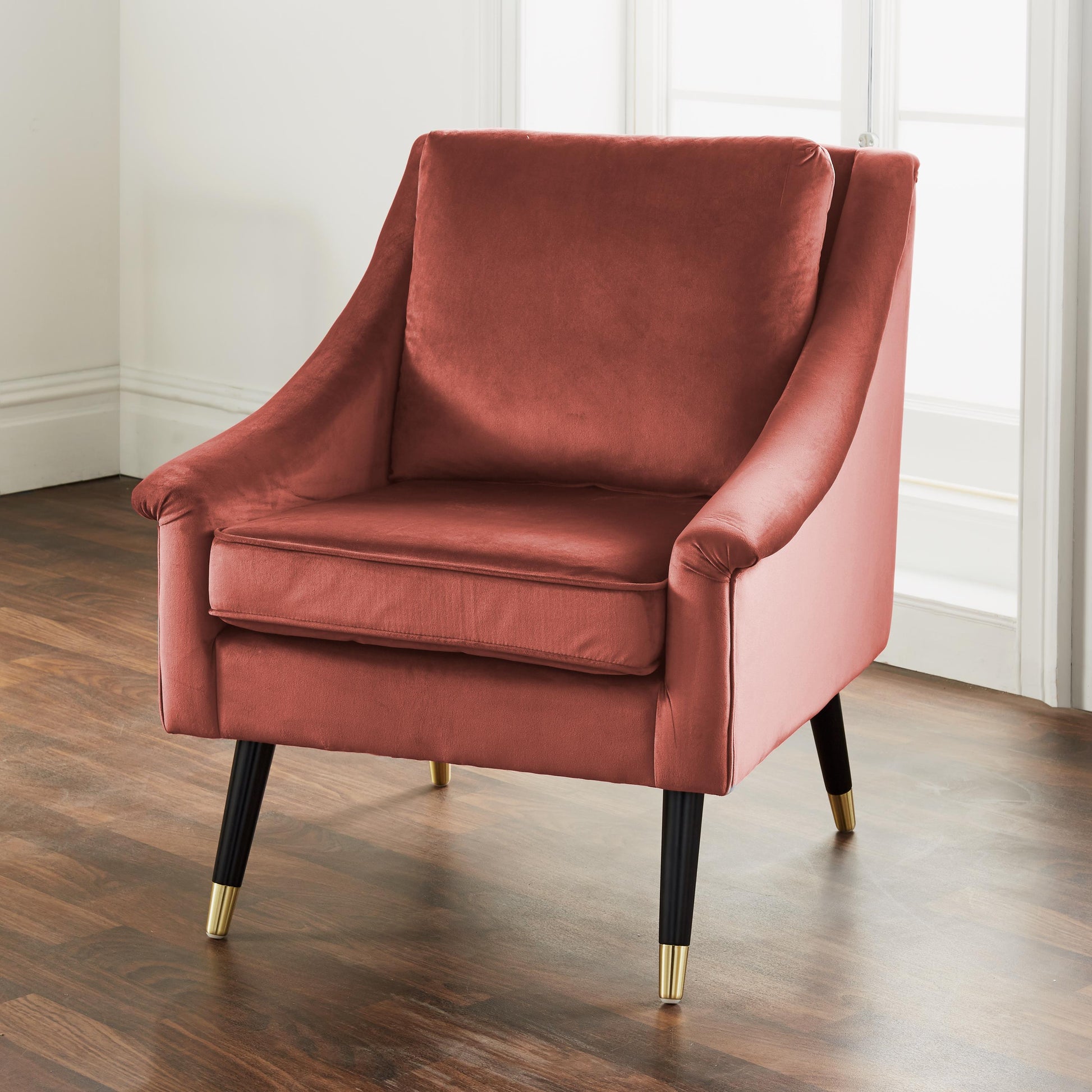 Fauteuil en velours rouge brique, accoudoirs arrondis et pieds noirs dorés