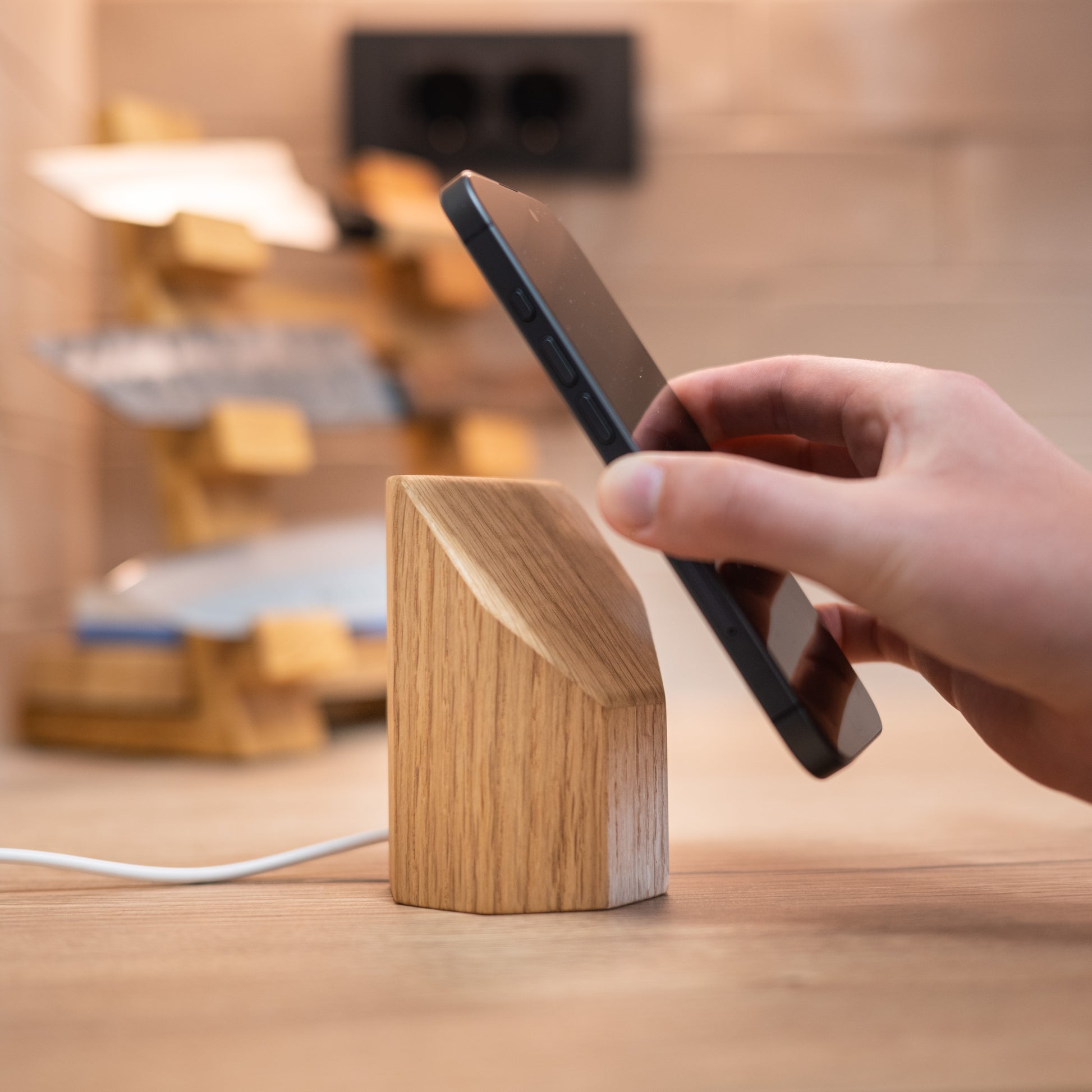 Chargeur sans fil sur socle en bois de chêne avec téléphone noir en charge