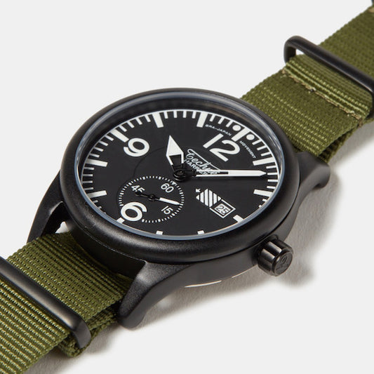 Montre tactique noire avec cadran noir et bracelet en toile vert olive, vue rapprochée.