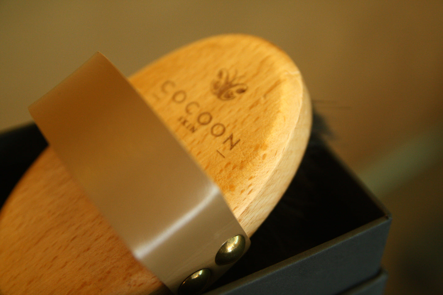 Brosse corporelle sèche COCOON SKIN : tête en bois, sangle beige et fixation à bouton.