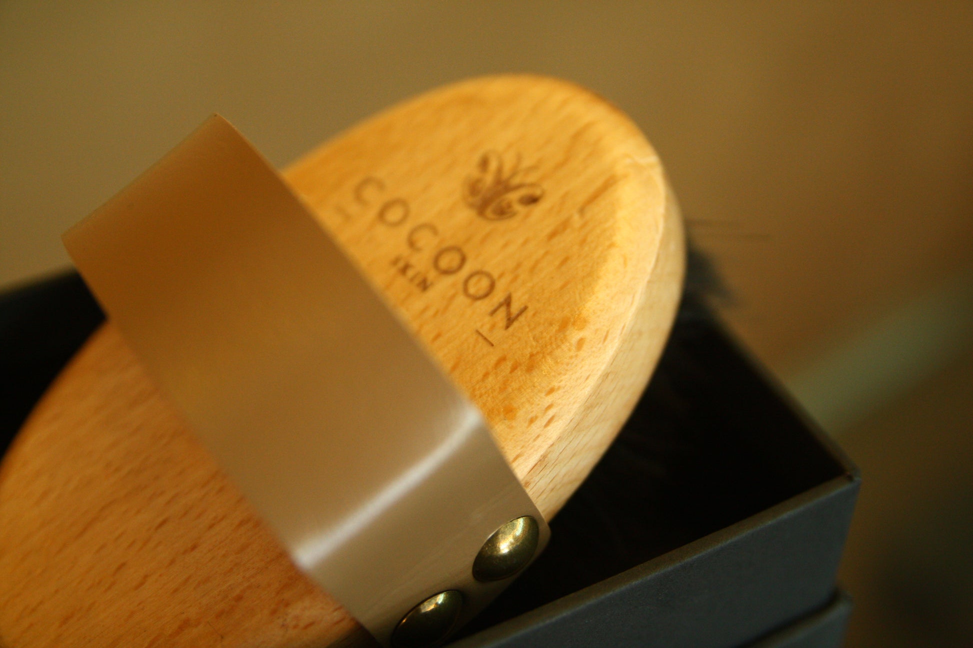 Brosse corporelle sèche COCOON SKIN : tête en bois, sangle beige et fixation à bouton.