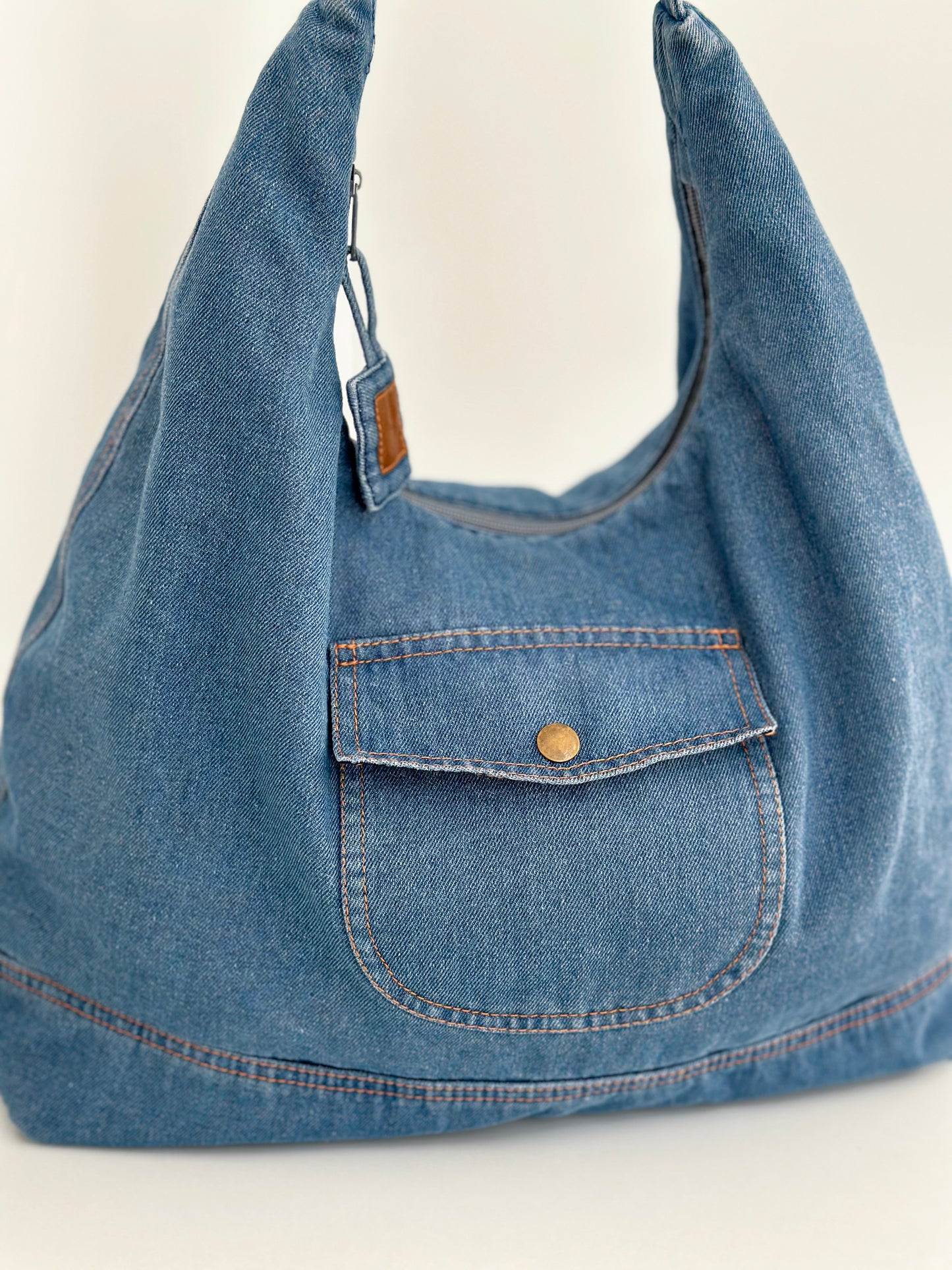 Sac hobo en denim bleu clair, grand volume, anses avec étiquette en cuir.