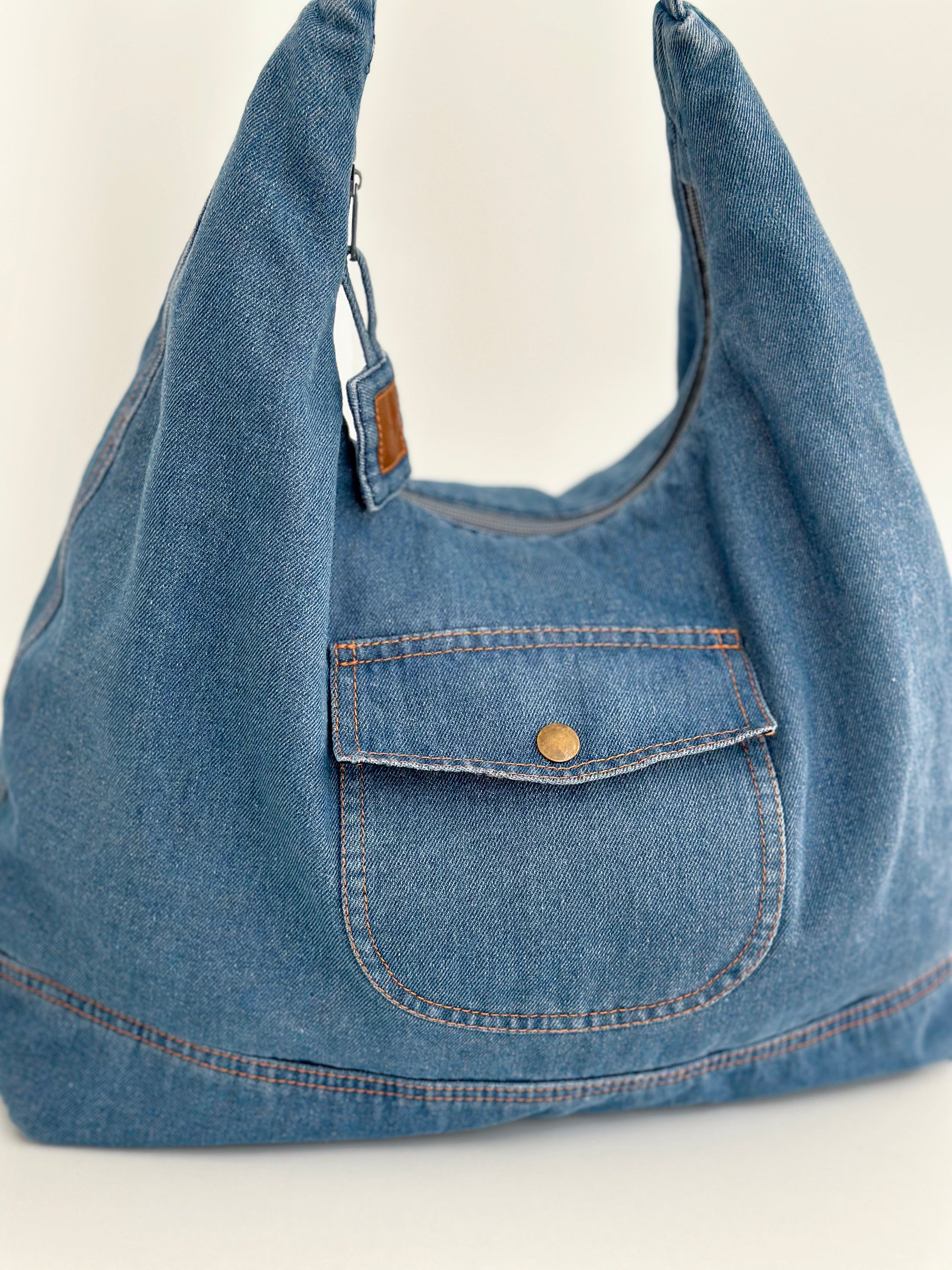 Sac hobo en denim bleu clair, grand volume, anses avec étiquette en cuir.