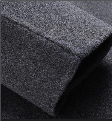 Manteau homme : bouton noir rond sur laine gris chiné, patte et couture visibles.