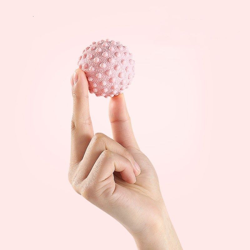 Balle de massage de yoga rose tenue dans la main, surface à picots.