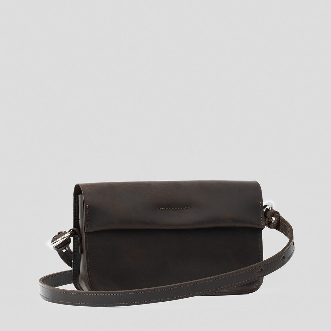 Sac bandoulière en cuir brun foncé, rabat arrondi et bandoulière à boucle