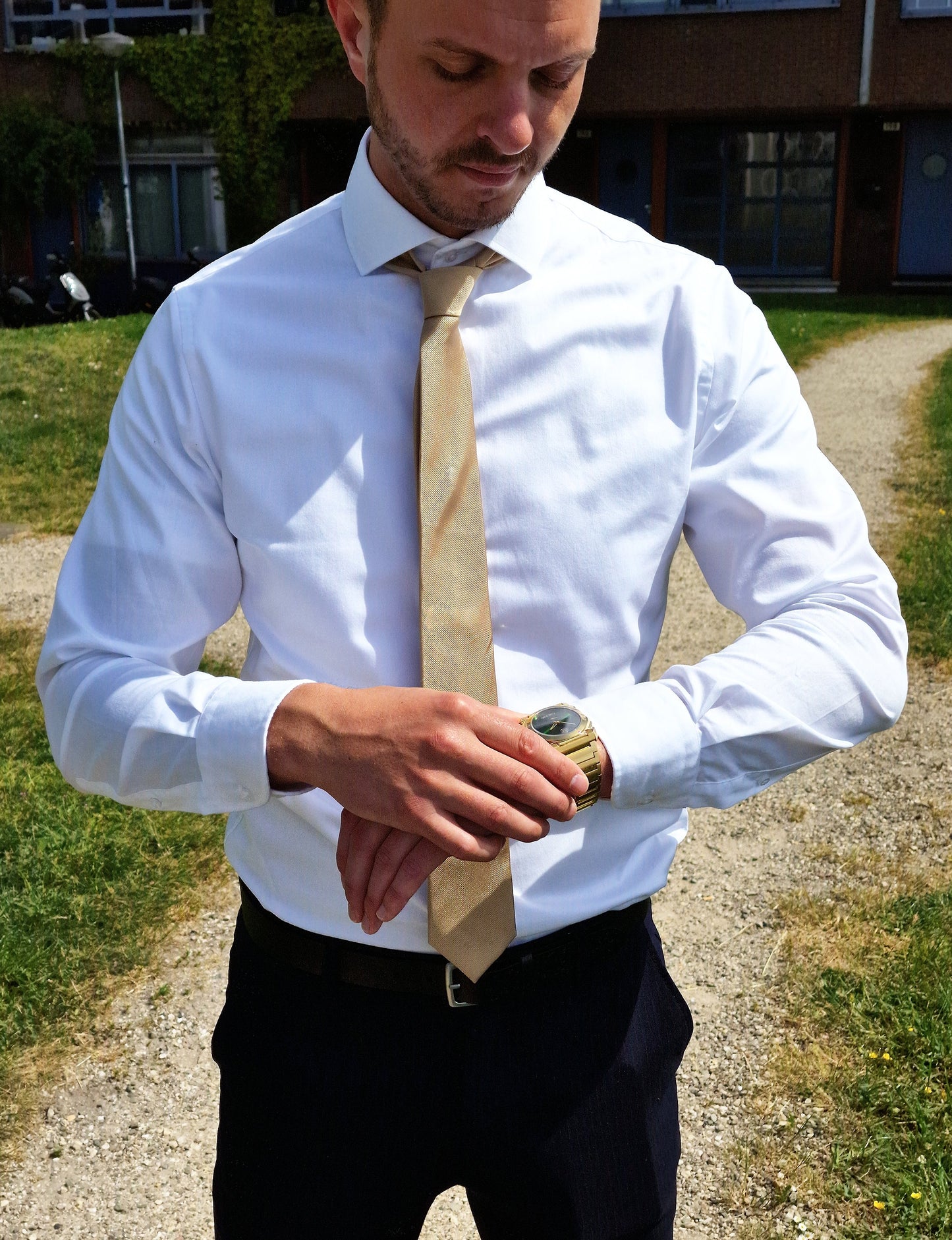 Montre-bracelet en acier doré sur poignet d’homme, cadran vert ajusté.