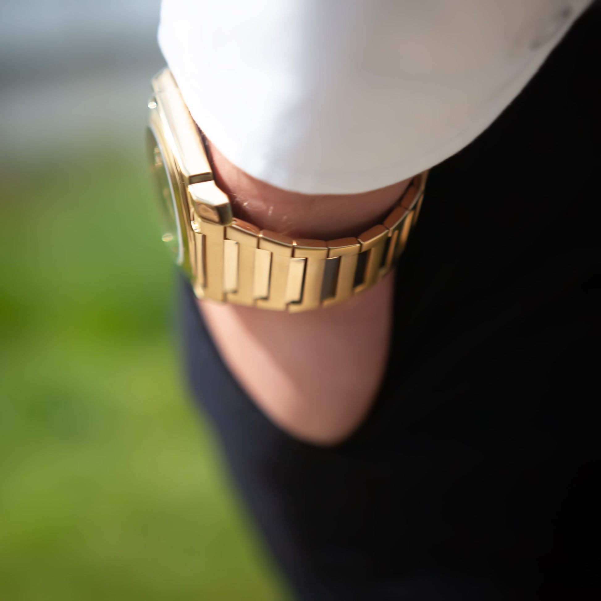 Montre-bracelet homme acier doré sur poignet, cadran vert, bracelet à maillons lisses.