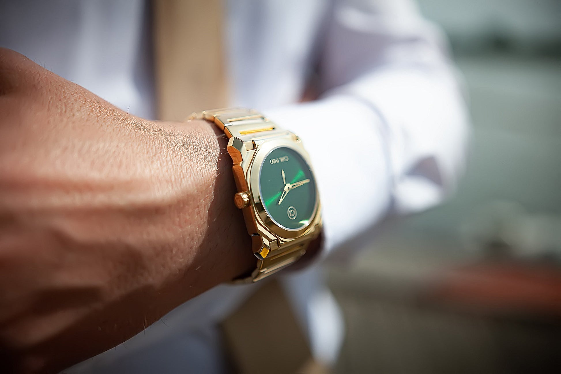 Montre-bracelet au poignet avec bracelet acier doré et cadran vert